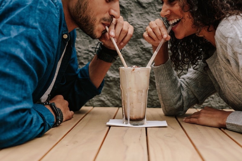 couple sharing milkshake flavoured with syrup